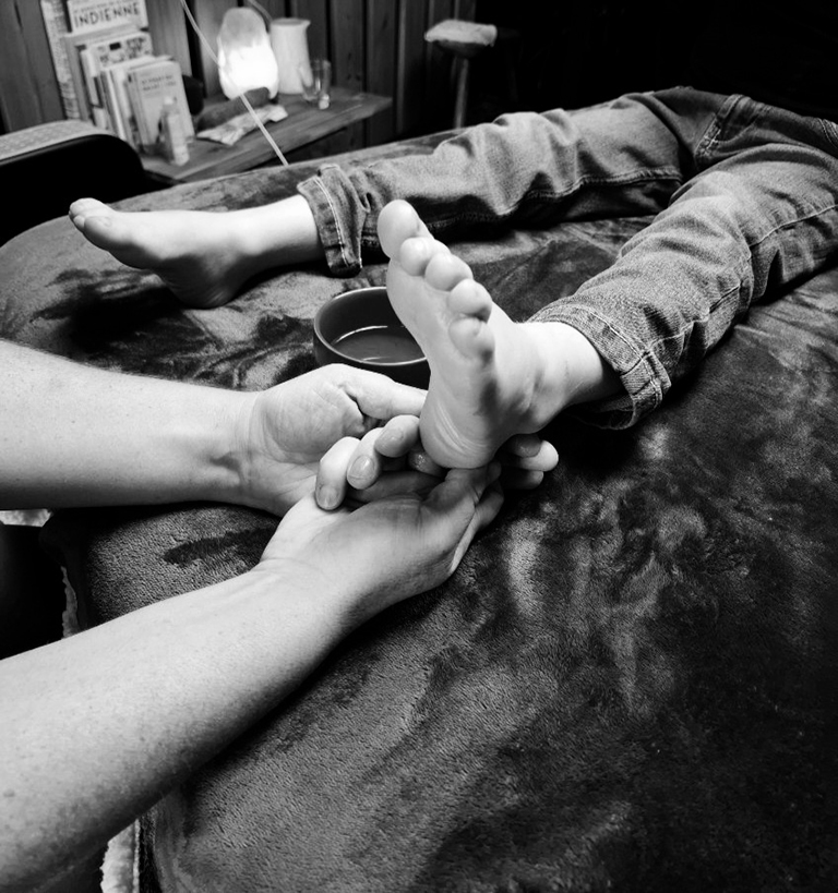 belle photo en noir et blanc d'une séance de réflexologie plantaire sur un enfant